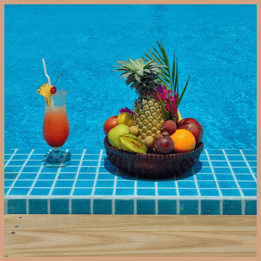 Tropical fruit basket and cocktail by poolside evoking Bora Bora scented soy candle tropical paradise escape