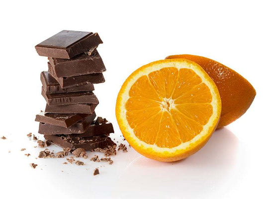 stacked chocolate pieces next to a halved fresh orange representing chocolate orange wax melt fragrance