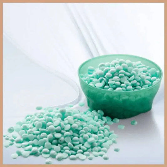 fresh turquoise carpet freshener beads in a green bowl and spilled on a white surface