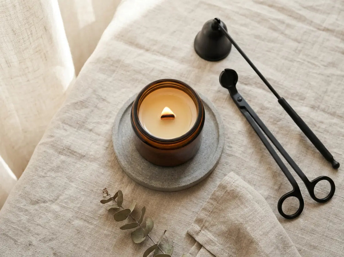 Lit jar candle with wick trimmer and candle snuffer on a heat-safe surface