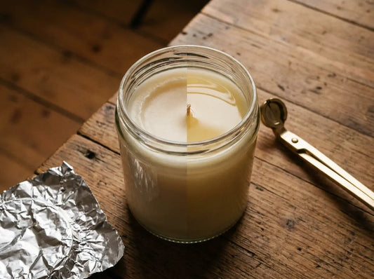 Jar candle showing tunnelling next to aluminium foil and a wick trimmer, with an even edge-to-edge melt pool shown for comparison