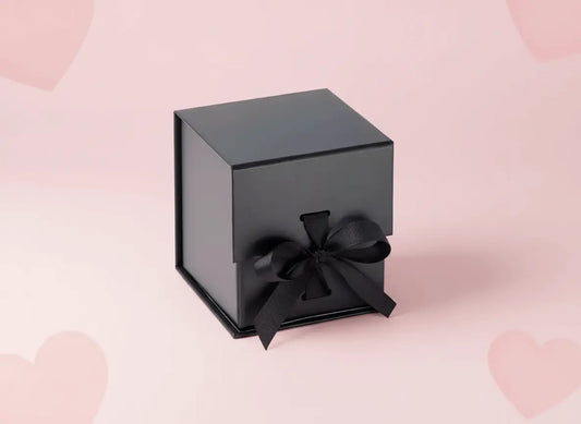 Luxury gift ideas 2026 UK in a sleek black gift box with a ribbon on a pastel pink background.