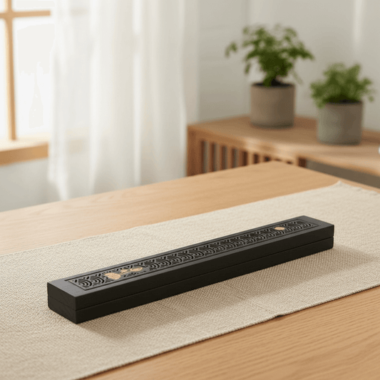 Black covered incense stick holder with lotus detail on a table
