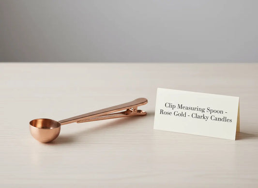 Clip Scooping Spoon - Rose Gold on a wooden table next to a product label from Clarky Candles.