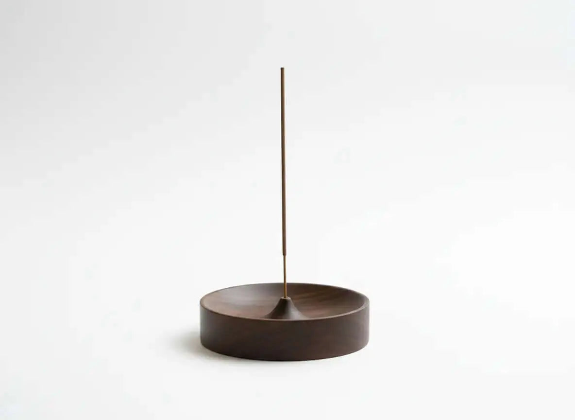 Solid wood incense stick holder with a minimal round ash catcher bowl and a single incense stick, photographed on a clean solid white background with soft studio lighting.